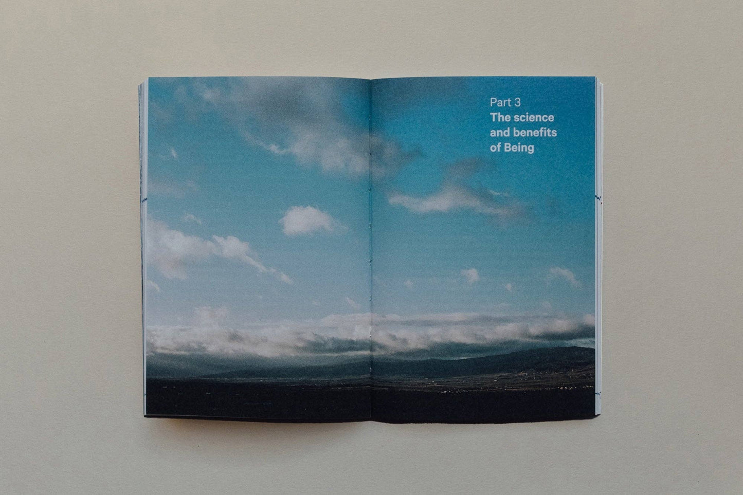 Open book showing a blue sky with clouds and text on a plain background