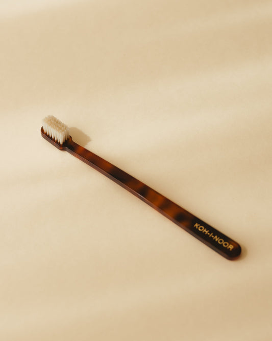 Koh-i-Noor Coccola Toothbrush with a stylish tortoiseshell design on a beige background.