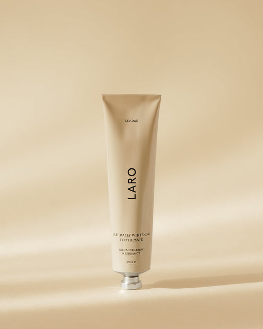 Naturally Whitening Toothpaste in a sleek tube design against a soft beige background.