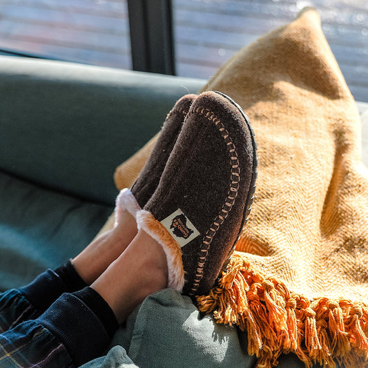 Pair of brown slippers with fur trim on someone foot