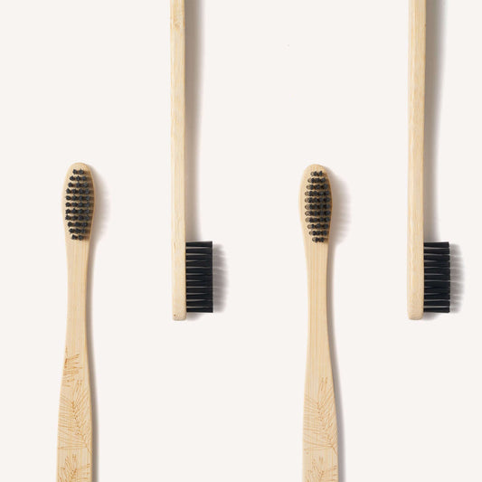 Two bamboo toothbrushes with black bristles on a white background