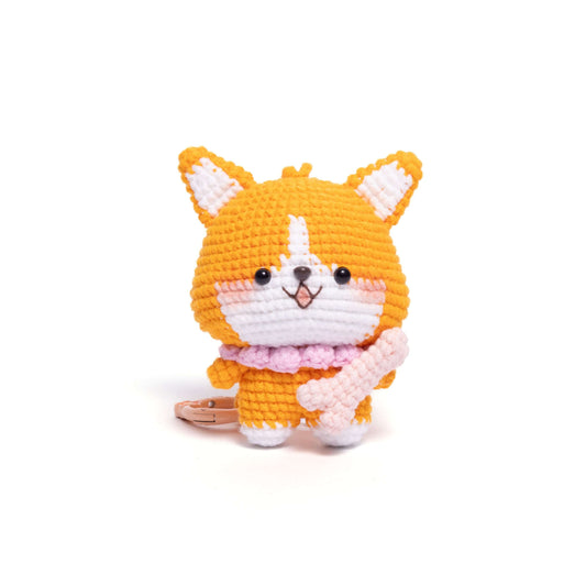 Crocheted toy cat with orange body, white face, and pink scarf on a white background