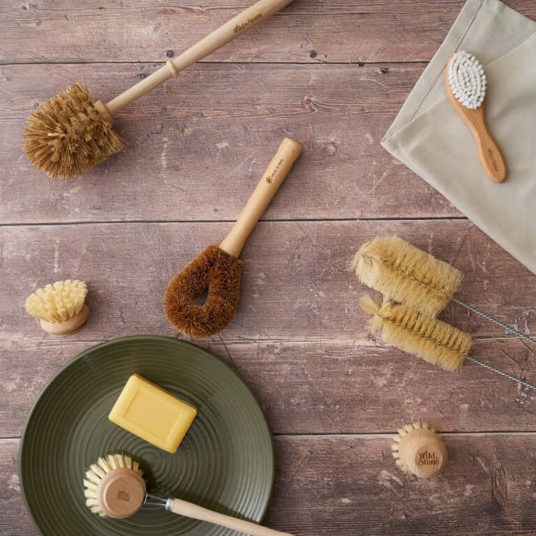 Set of natural cleaning brushes and a bar of soap on a wooden surface
