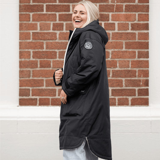 Woman smiling in a black raincoat, showcasing the Raincoat & Changing Robe in One - The Classic Cobe Black.