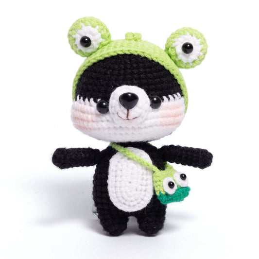 Crocheted panda plush toy with a green hat and backpack on a white background