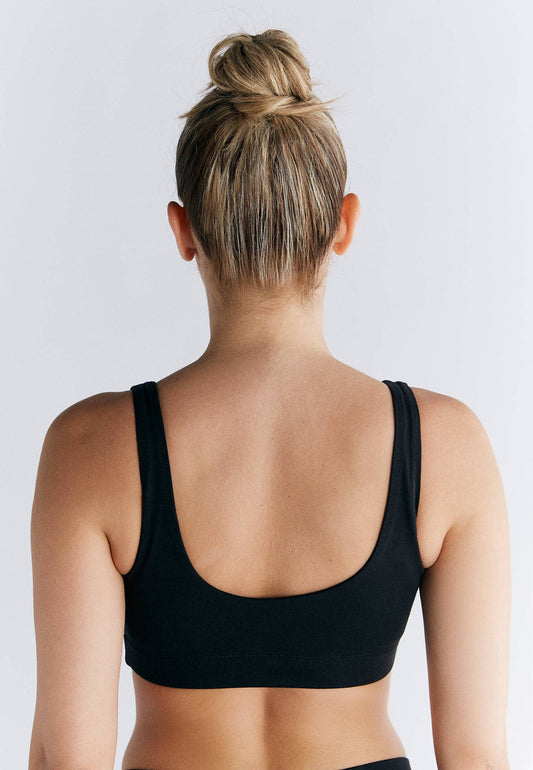 Back view of a model wearing an Organic Cotton Padded Bralette in black, showcasing its sleek and supportive design.