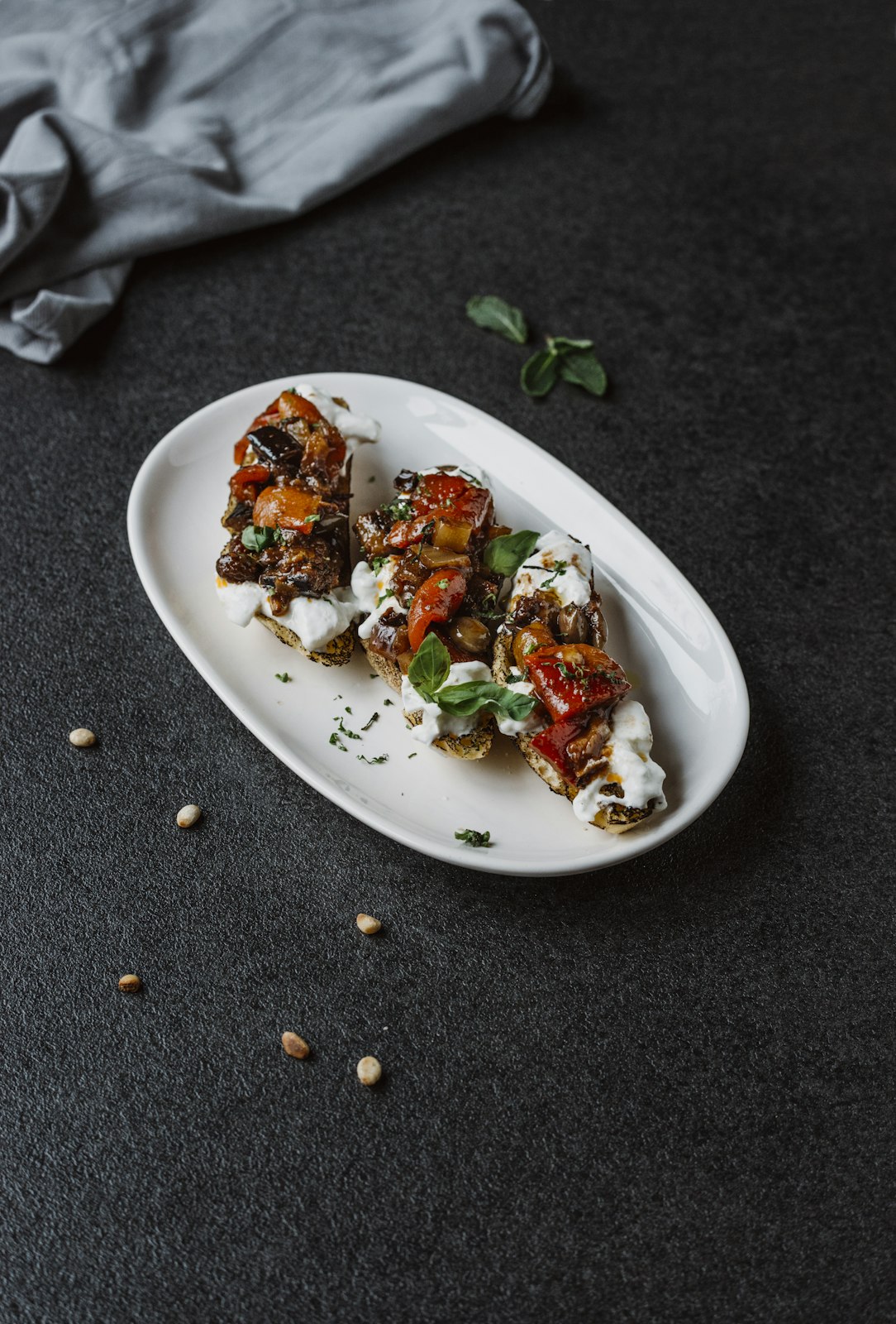 Plated dish of roasted vegetables with cheese on a dark surface