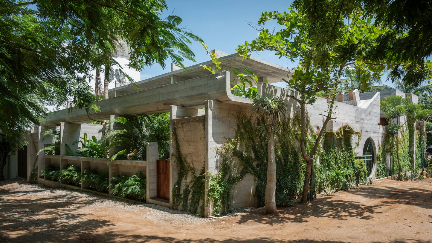 Modern building with greenery integrated into its design, surrounded by trees.