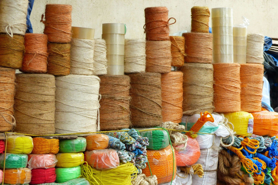 Various spools of yarn and thread stacked in a textile market, highlighting sustainable materials related to UK Advances Circular Textiles Infrastructure: Fashion’s Next Revolution.