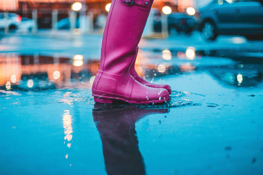 The Toxic Truth About PFAS: Why ‘Forever Chemicals’ in Fashion Must Go - Pink rain boots splashing in a puddle.