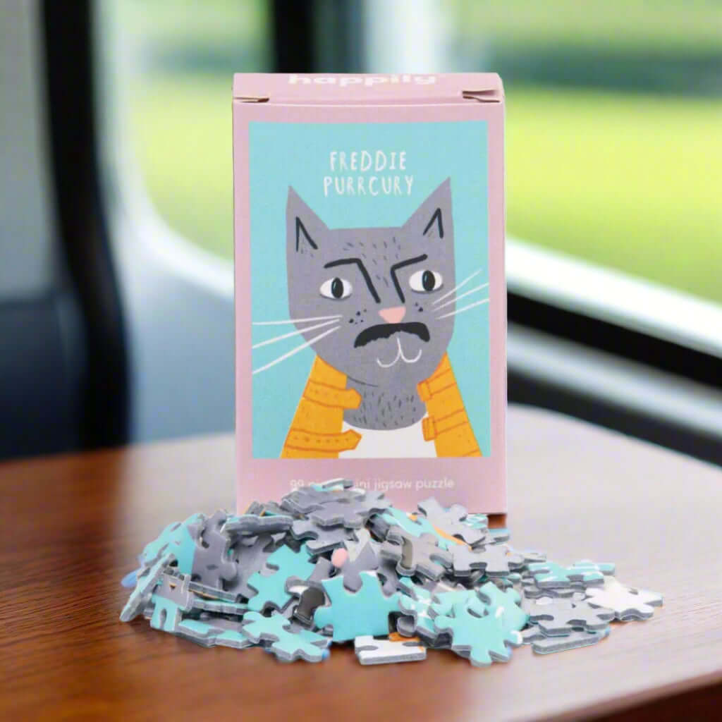 Freddie Purrcury 99-piece mini cat jigsaw puzzle packaging with scattered puzzle pieces on white background, funny eco-friendly gift UK from ALEWK.CLUB