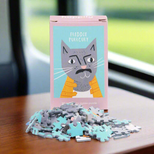 Freddie Purrcury 99-piece mini cat jigsaw puzzle packaging with scattered puzzle pieces on white background, funny eco-friendly gift UK from ALEWK.CLUB