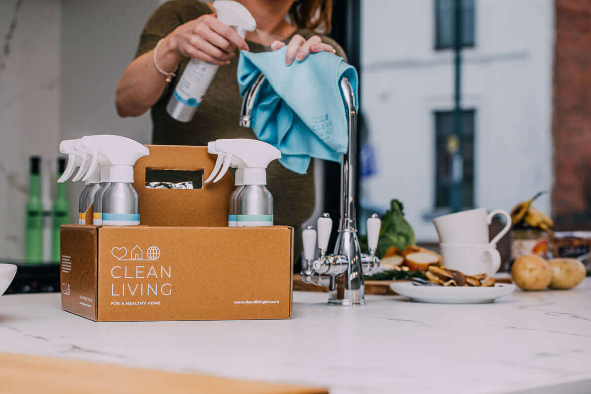 Sustainable Home Cleaning Essentials kit displayed on kitchen counter with cleaning supplies and eco-friendly cloth.