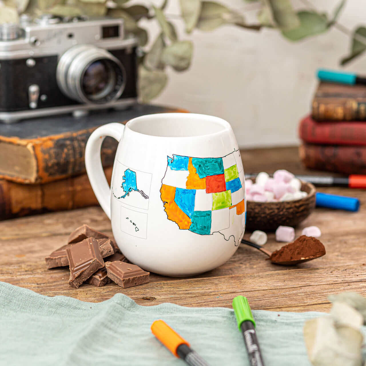 Ceramic mug featuring a colorful map of the United States, styled with a rustic background and craft supplies.
