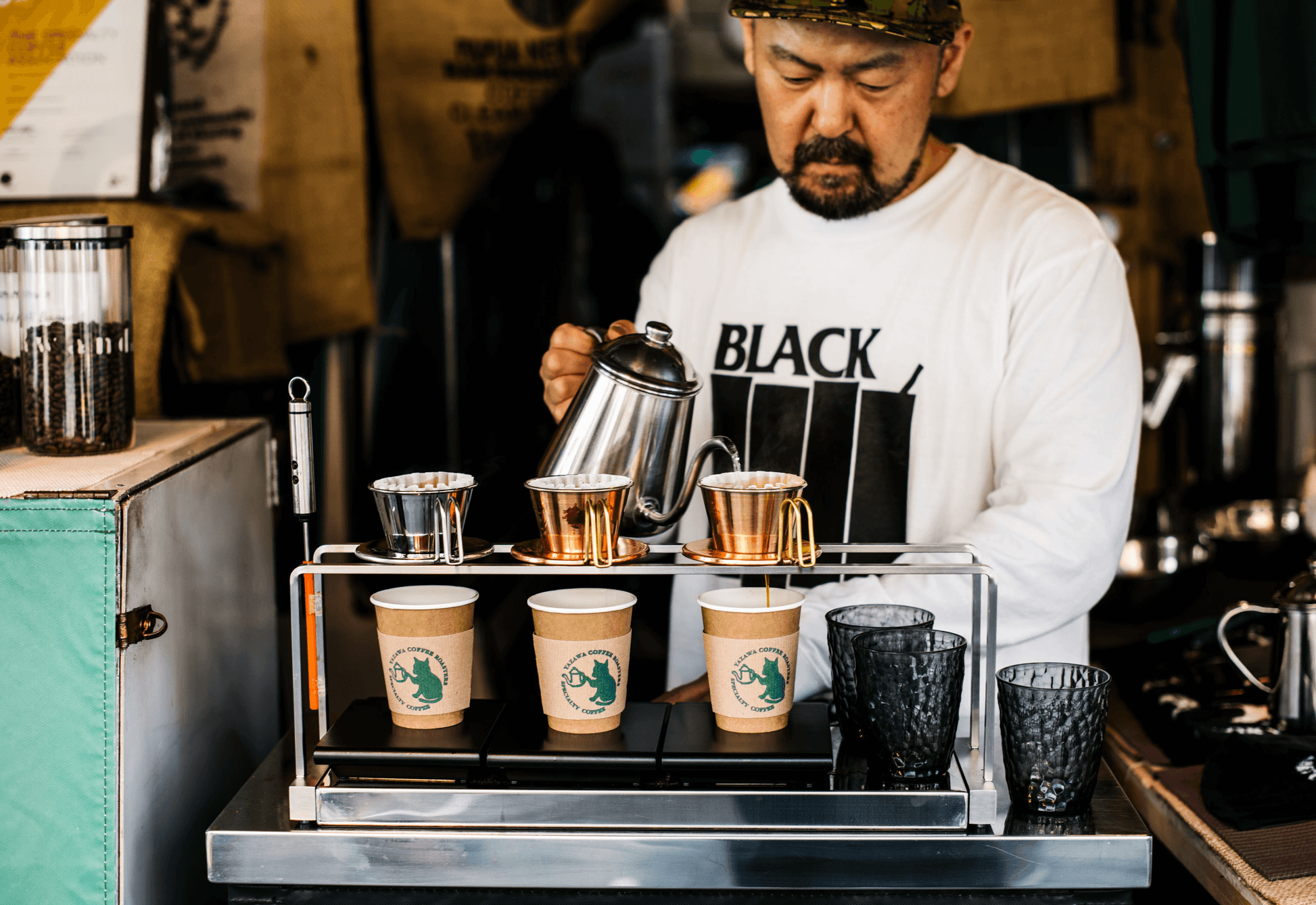 Barista preparing coffee at a coffee shop with various coffee-making equipment and cups.
