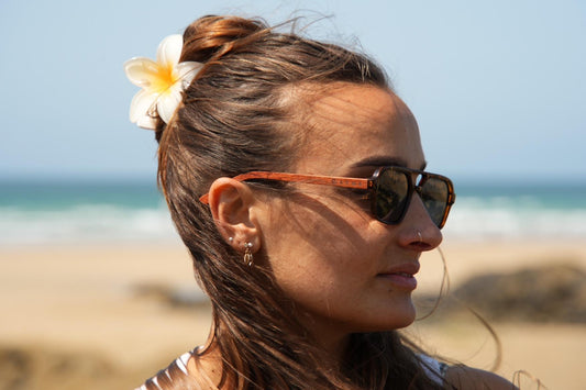 Woman with sunglasses and a flower in her hair on a beach