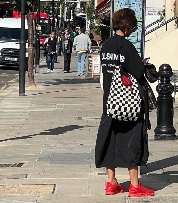 Person walking on a city street with a checkered bag