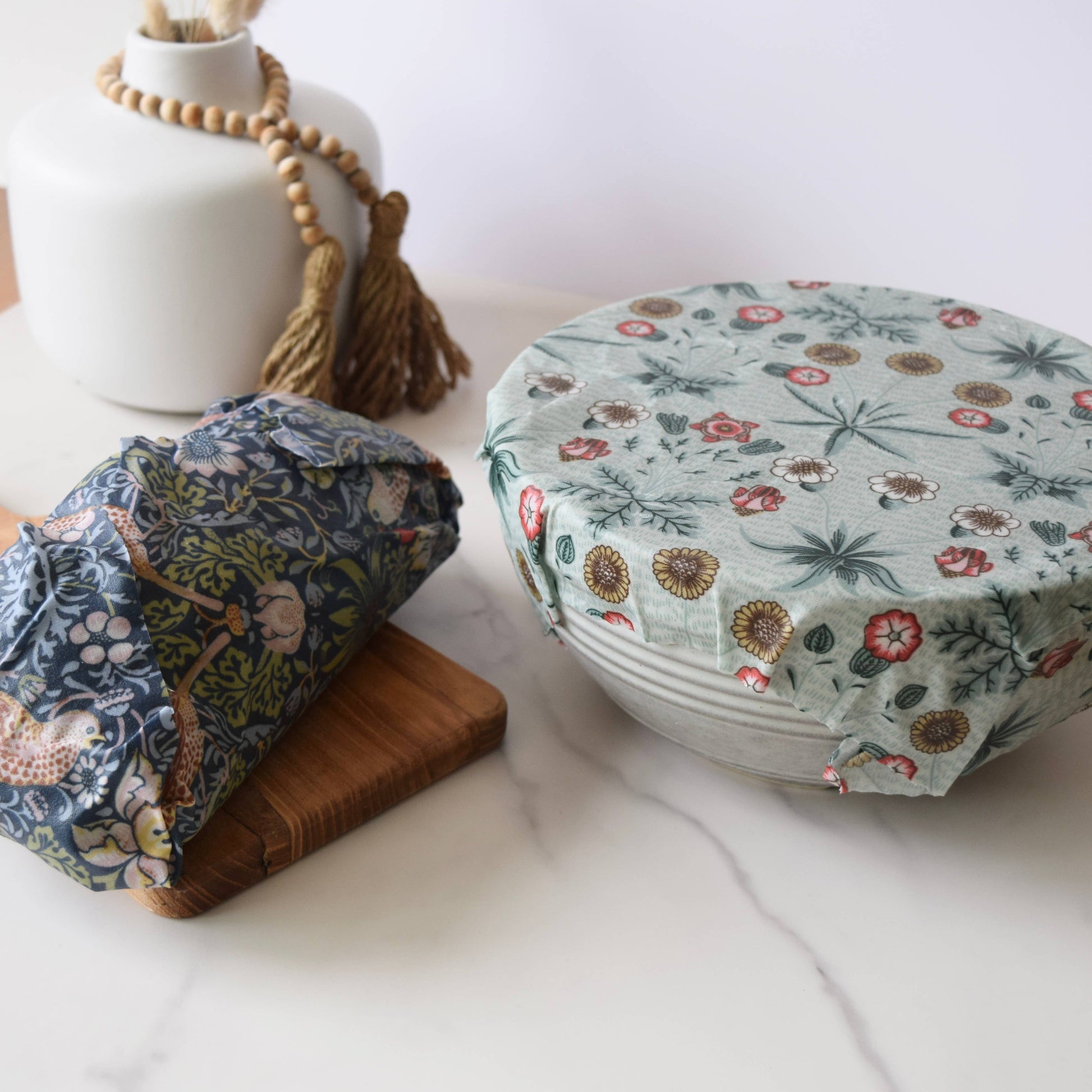 Fabric-wrapped bowls on a white surface with a vase in the background