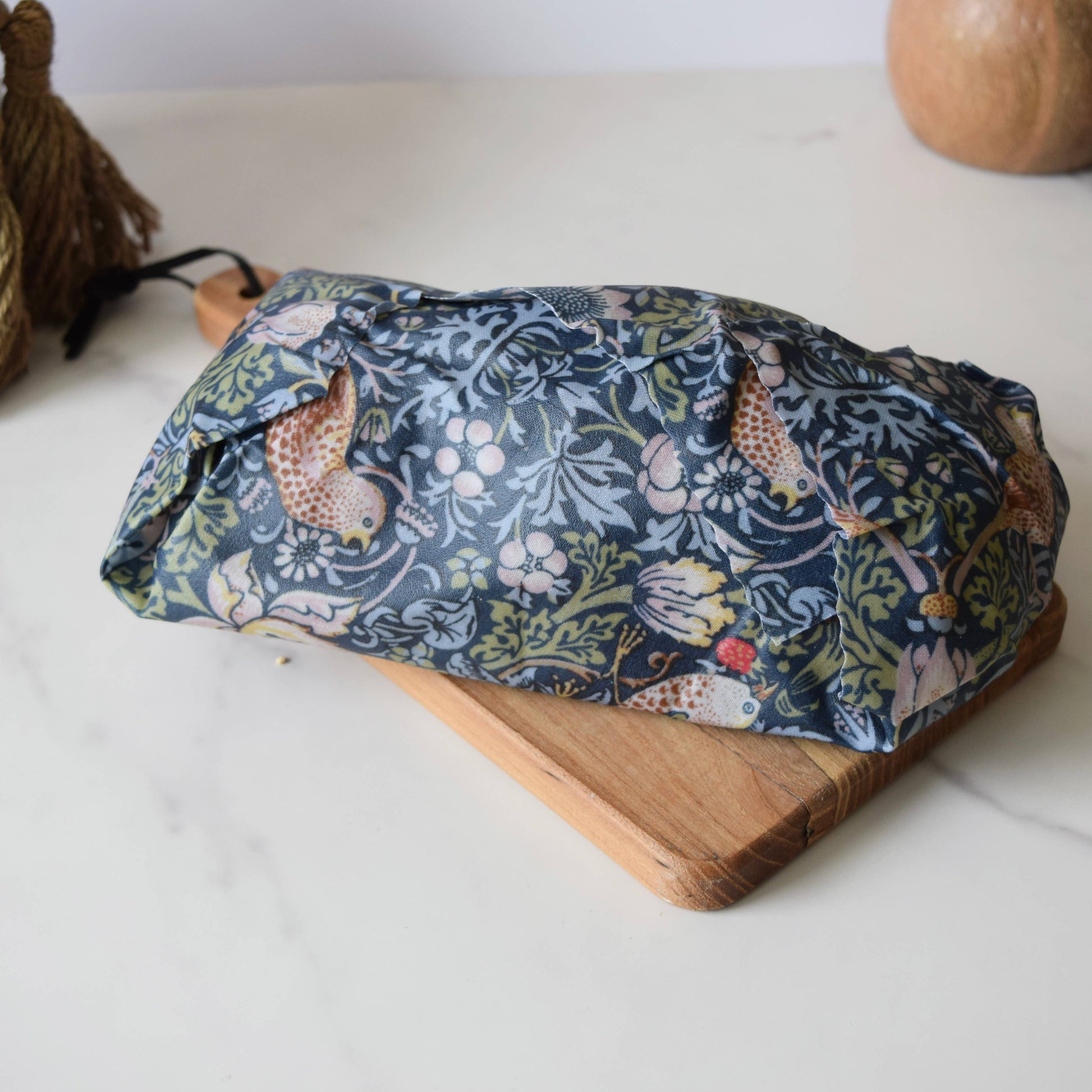 Floral-patterned fabric roll on a wooden board with a white background