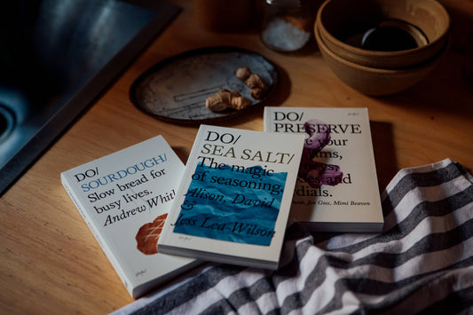 Three books on a wooden surface with a checkered cloth underneath