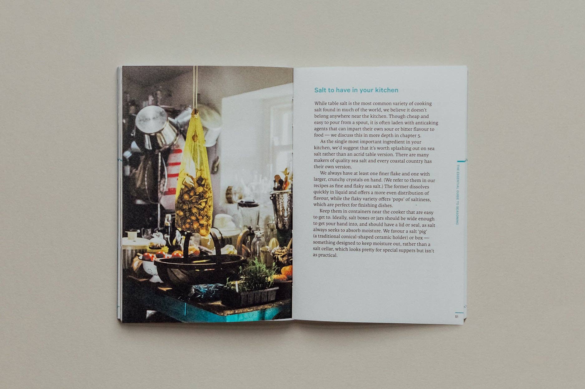 Open book showing a kitchen interior with text on a neutral background