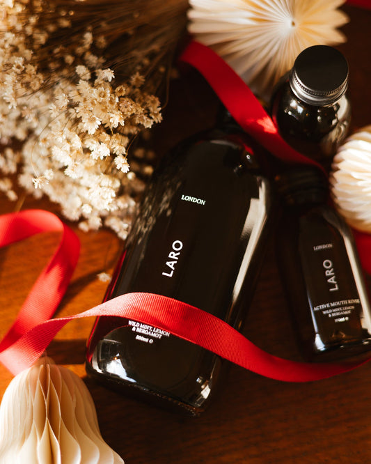 LARO Active Mouth Rinse, 500ml bottle with elegant decorations and a red ribbon on a wooden surface.