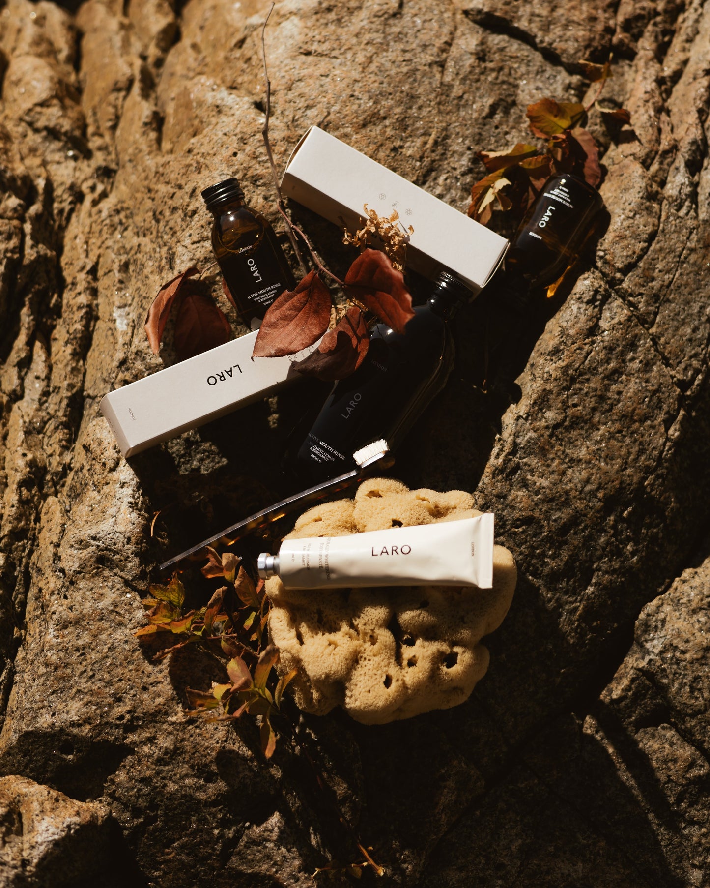 Travel Mouth Rinse, 100ml products displayed among natural elements on a rocky surface.