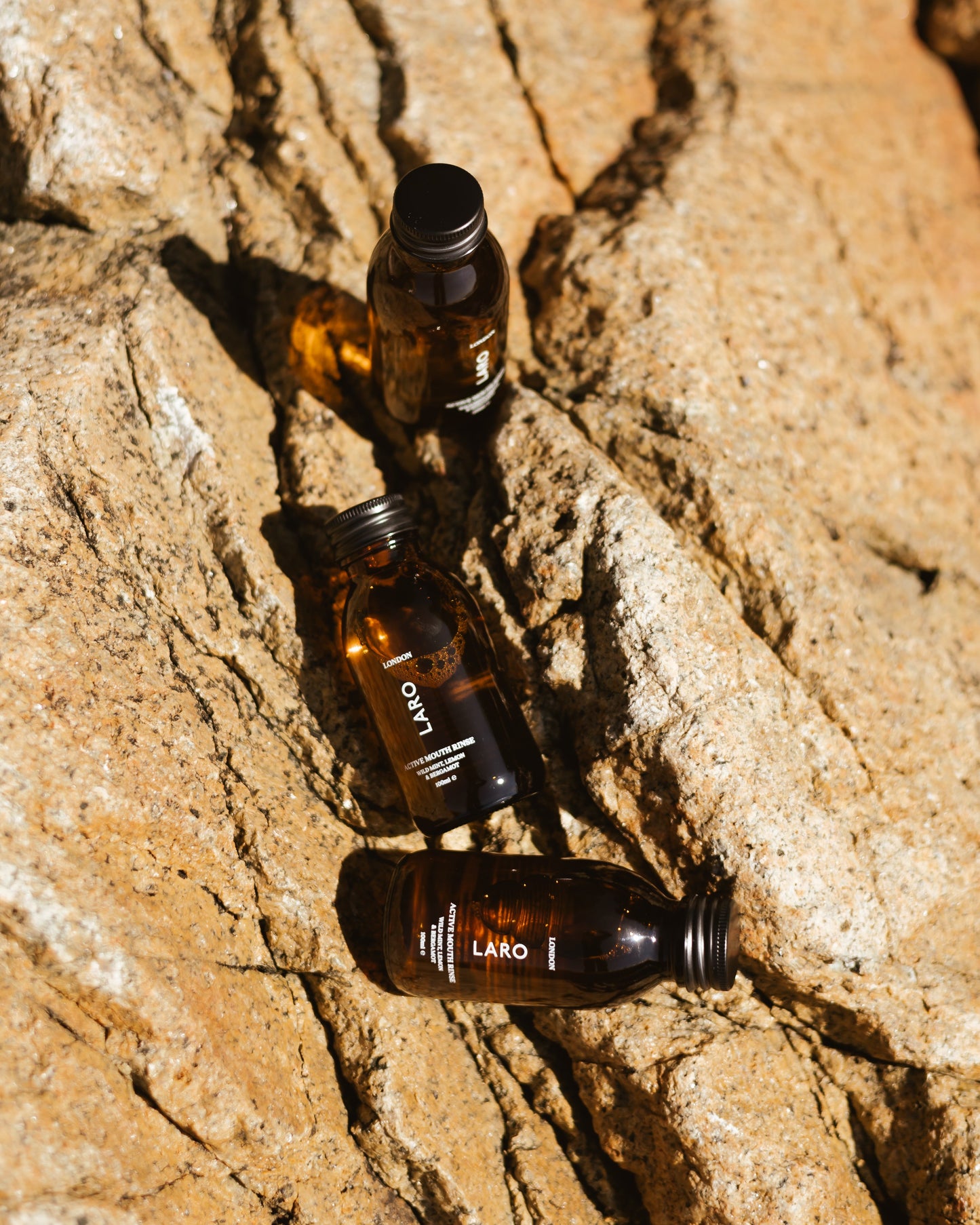 Travel Mouth Rinse, 100ml bottles arranged on rocky surface, showcasing their travel-friendly design.