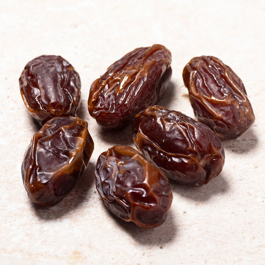 Six dried dates on a textured beige surface