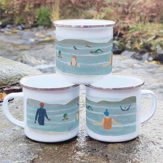 Three enamel mugs with scenic illustrations of people in a lake on a stone surface.