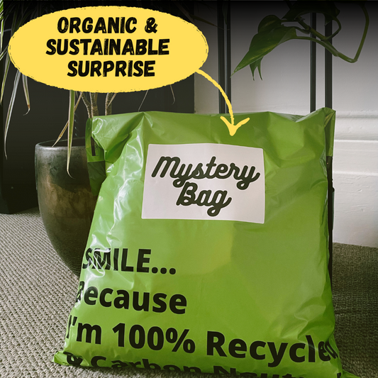 Green mystery bag with text about sustainability and recycling, placed on a surface with a plant in the background.