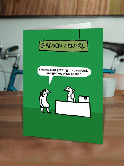 Modern Toss Garden Centre greetings card standing on a wooden shelf