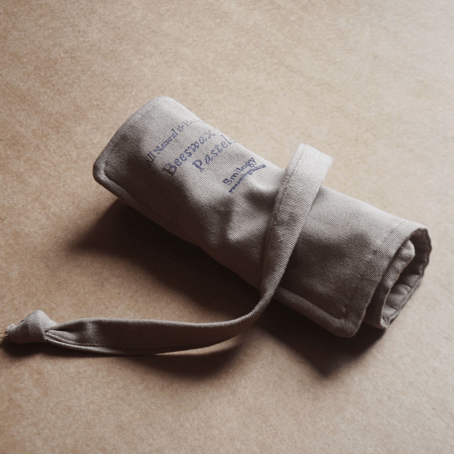 Rolled-up beige fabric pouch with text on a beige background