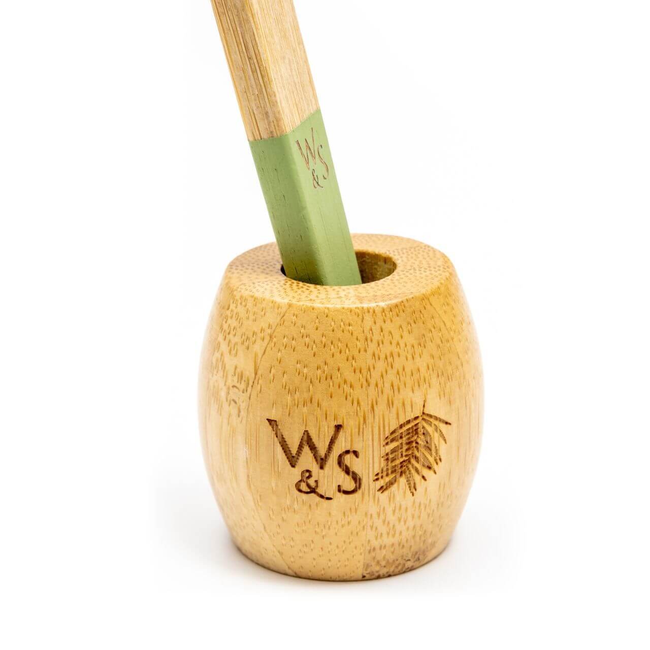 Bamboo utensil with green handle in wooden holder on white background