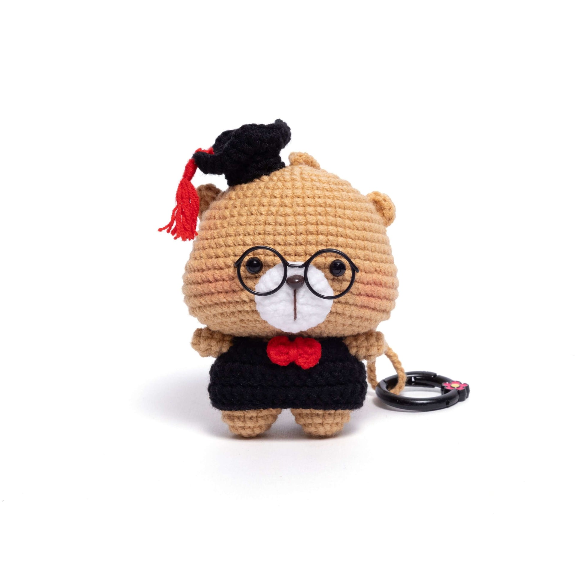 Small plush toy with glasses and a graduation cap on a white background