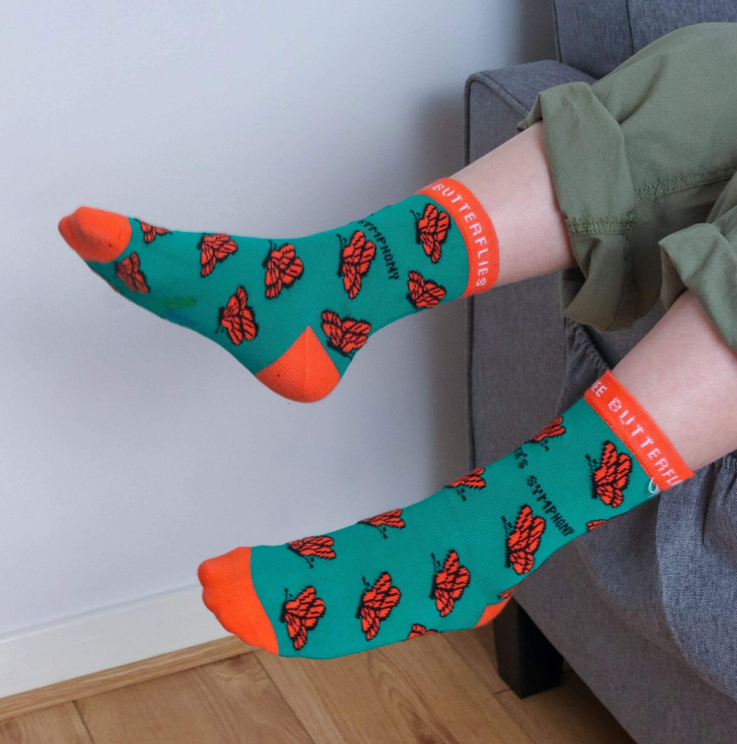 CAREFREE BUTTERFLIES ORGANIC COTTON KIDS SOCKS displayed on a child's feet with green and orange butterfly patterns.