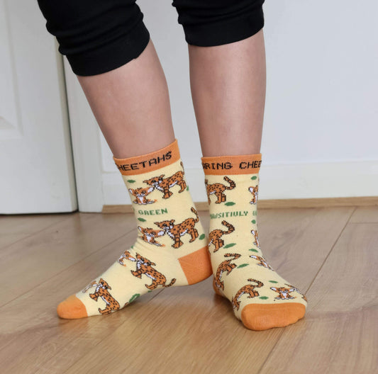 Person wearing socks with cheetah print and text on a wooden floor.