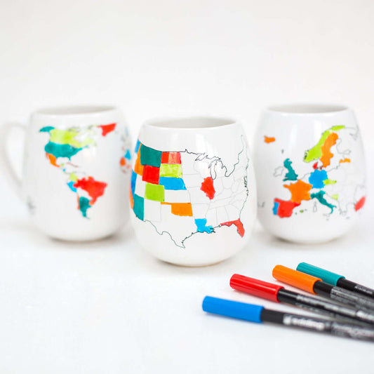 Three mugs with world map designs and markers on a white background