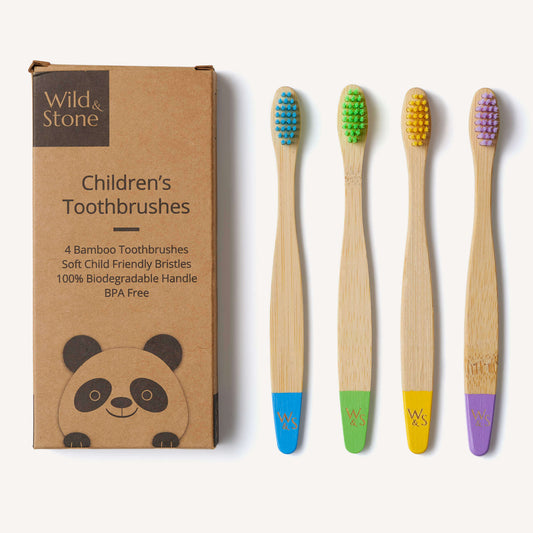Set of four children's bamboo toothbrushes with colored bristle heads next to their packaging.