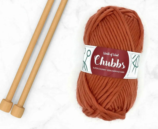 Cinnamon Merino Super Chunky Weight yarn in Spicy Orange with wooden knitting needles.