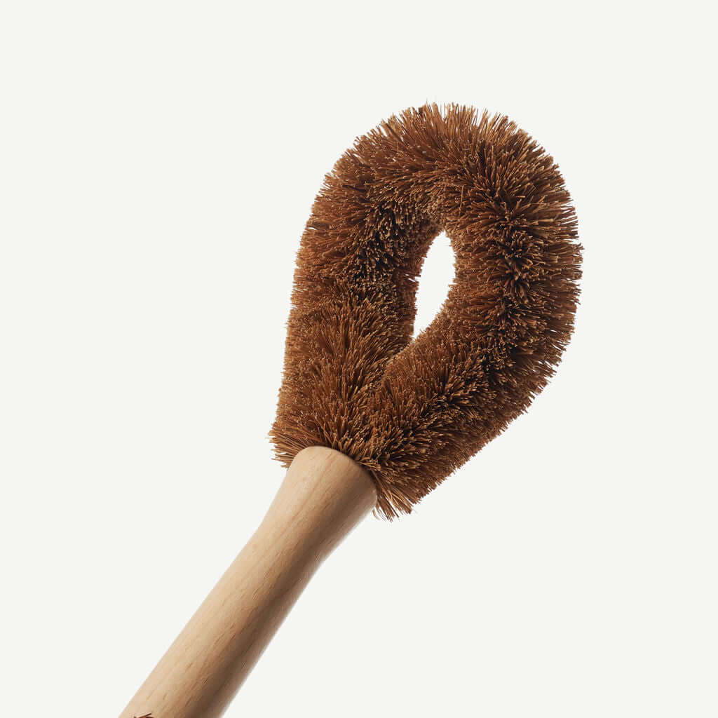 Dish brush with brown bristles and wooden handle on a white background