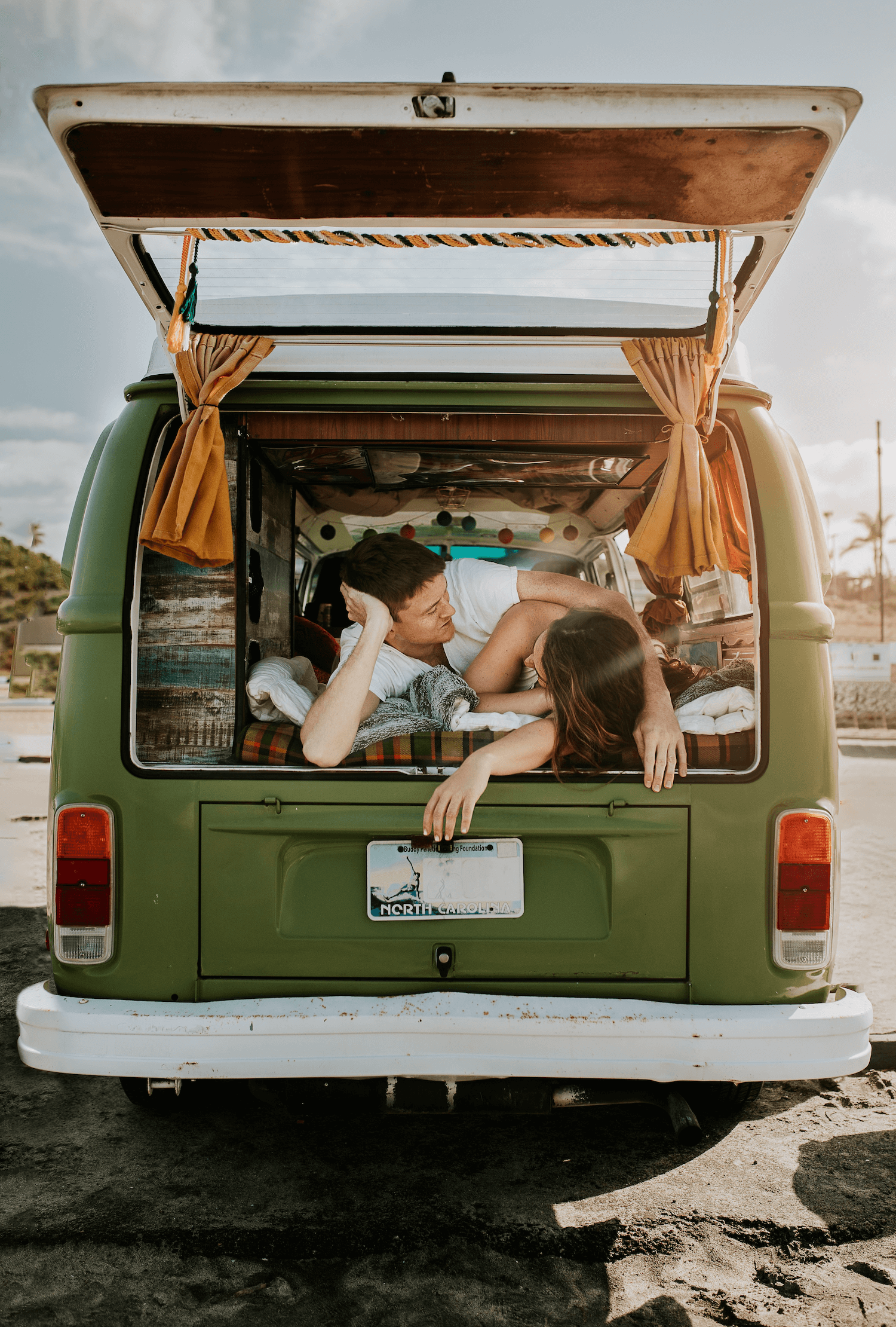 Two people lying inside an open van with a scenic background