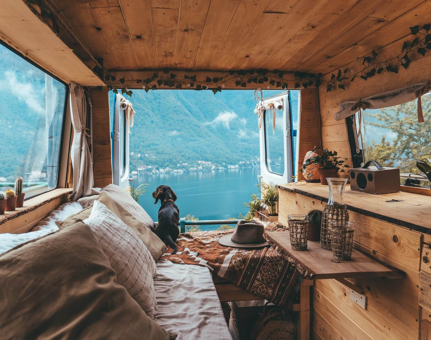 Cozy interior of a wooden cabin with a view of a lake and mountains.