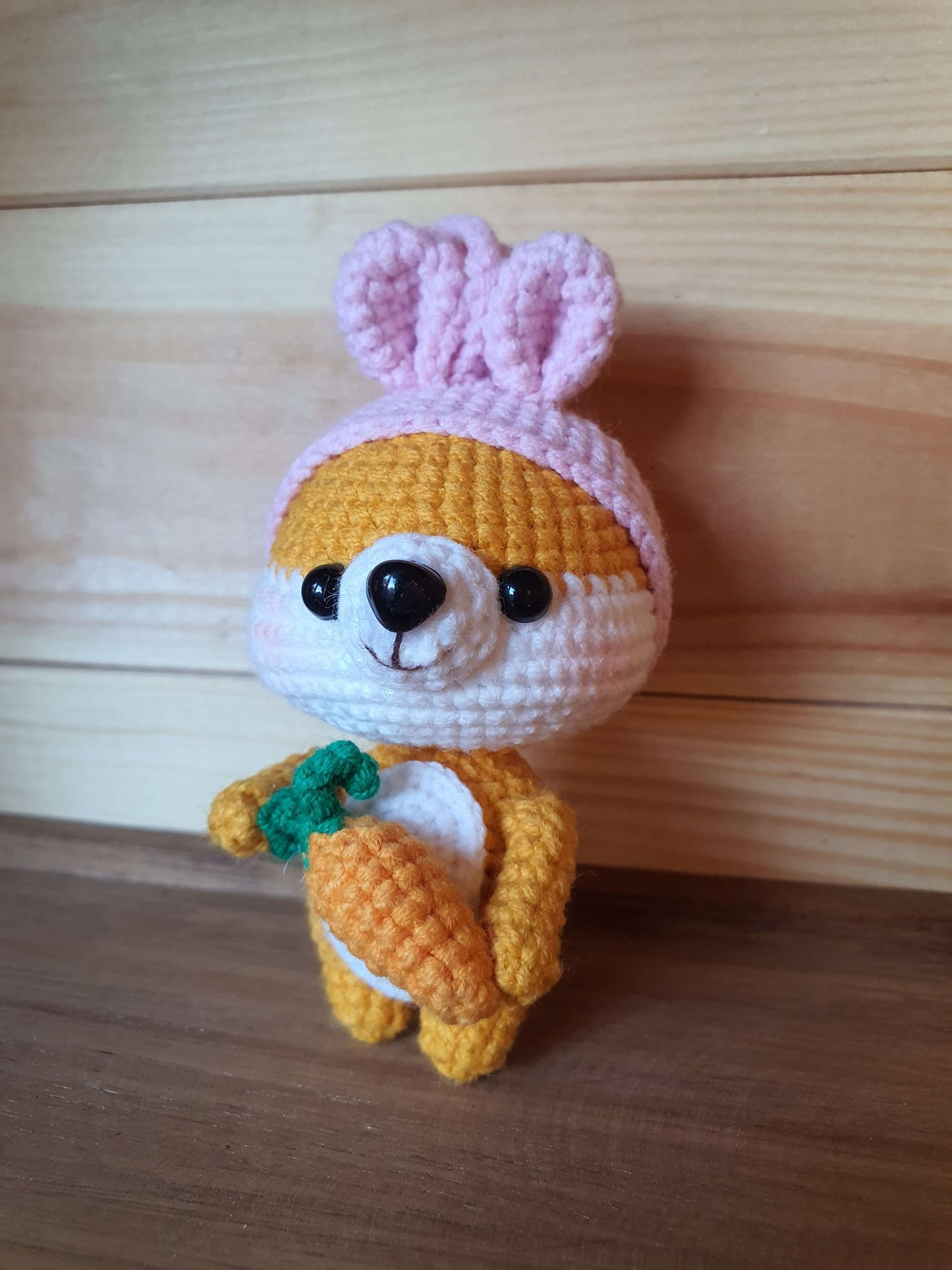 Crocheted toy bear in a bunny costume on a wooden surface