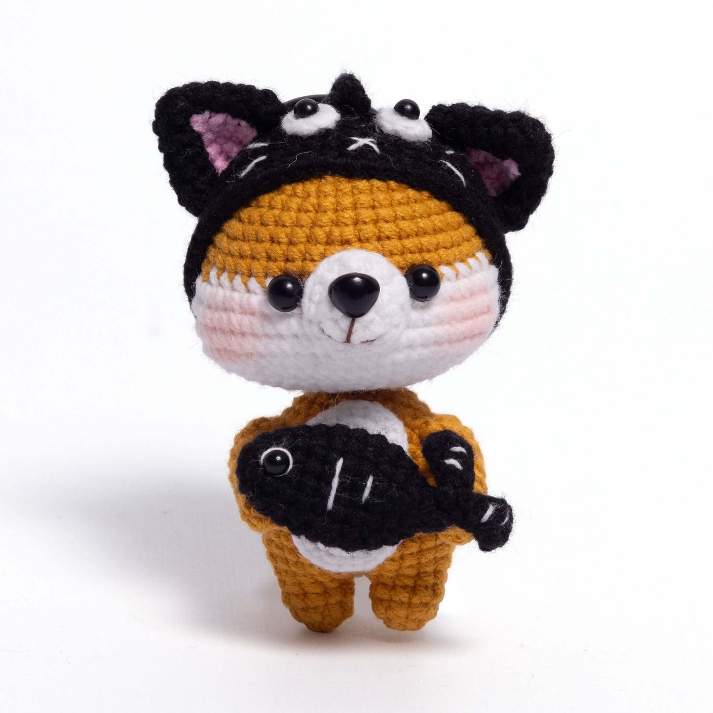 Crocheted animal toy with a black hat on a white background