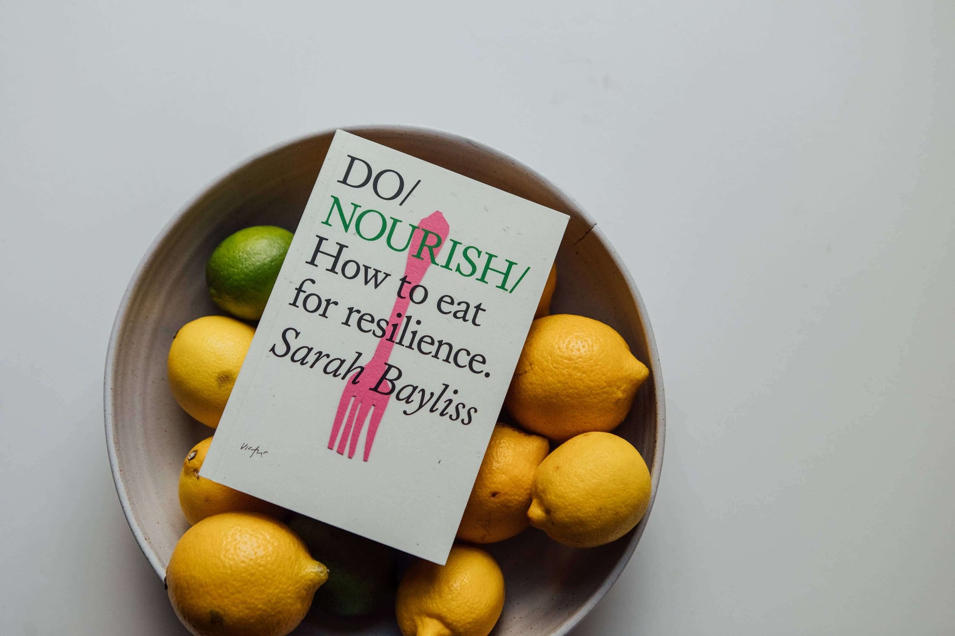 Nutrition Book Do Nourish by Sarah Bayliss - Do Books on a bowl of lemons and limes.