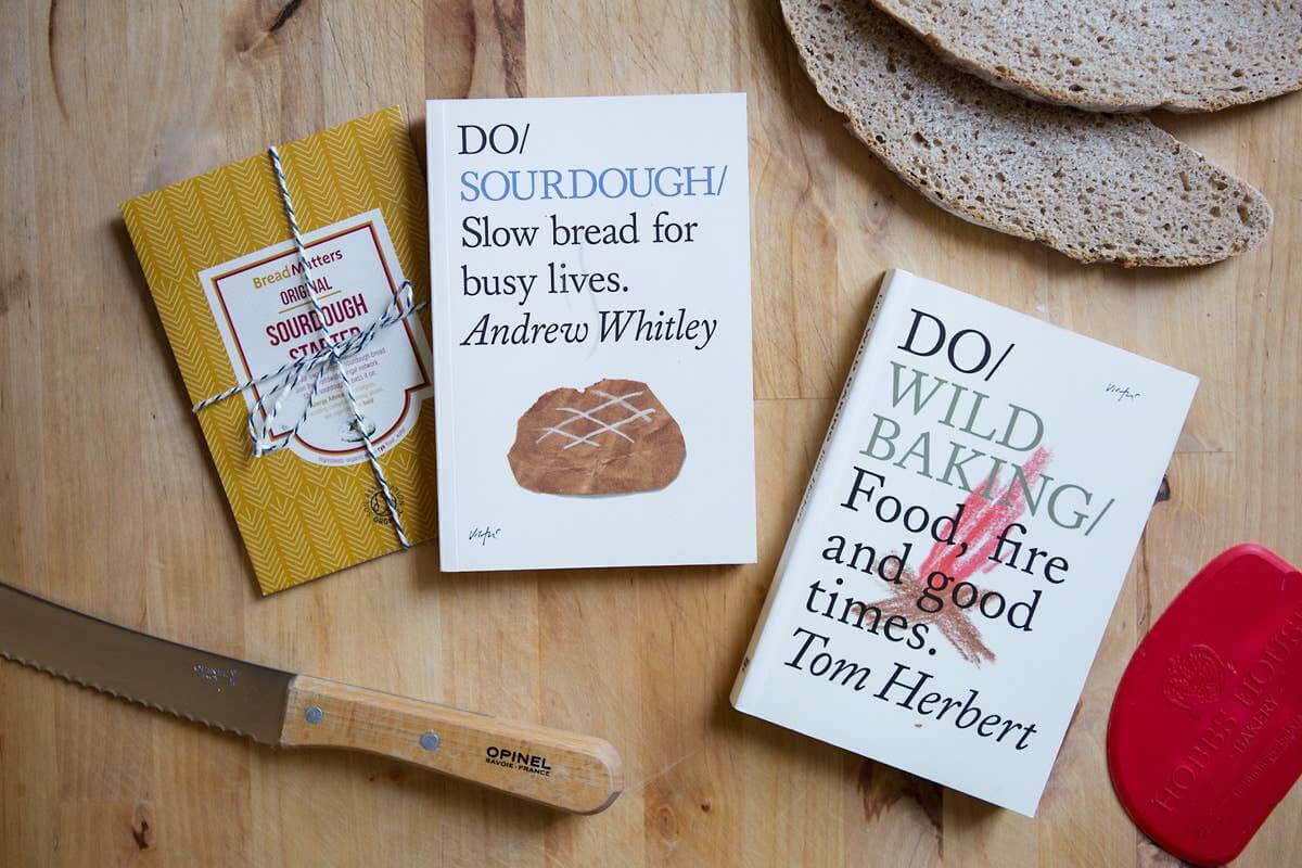 Two books on a wooden surface with bread and a knife.