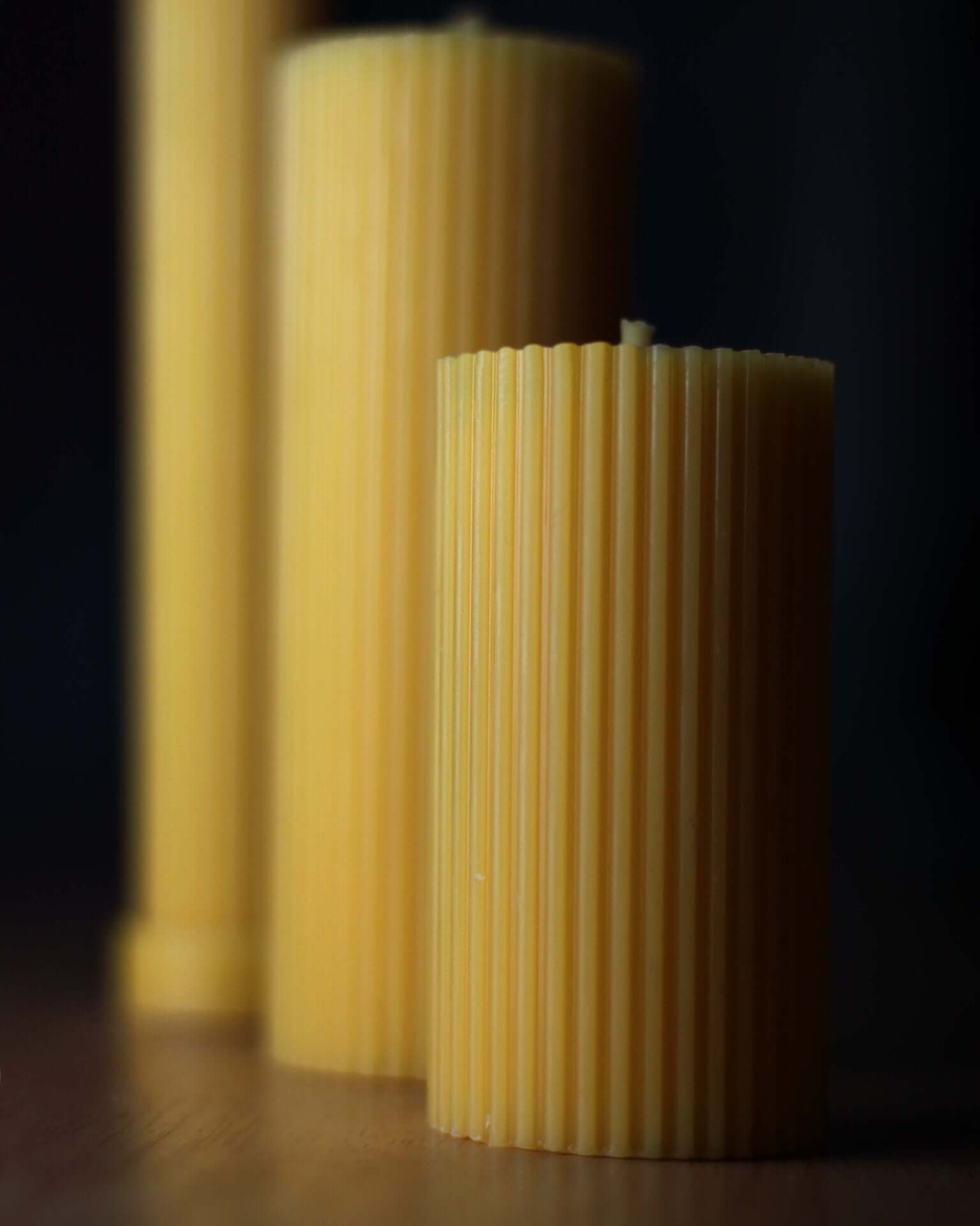 Set of 3 cylinders made of pure beeswax, showcasing their unique ribbed texture and natural color.