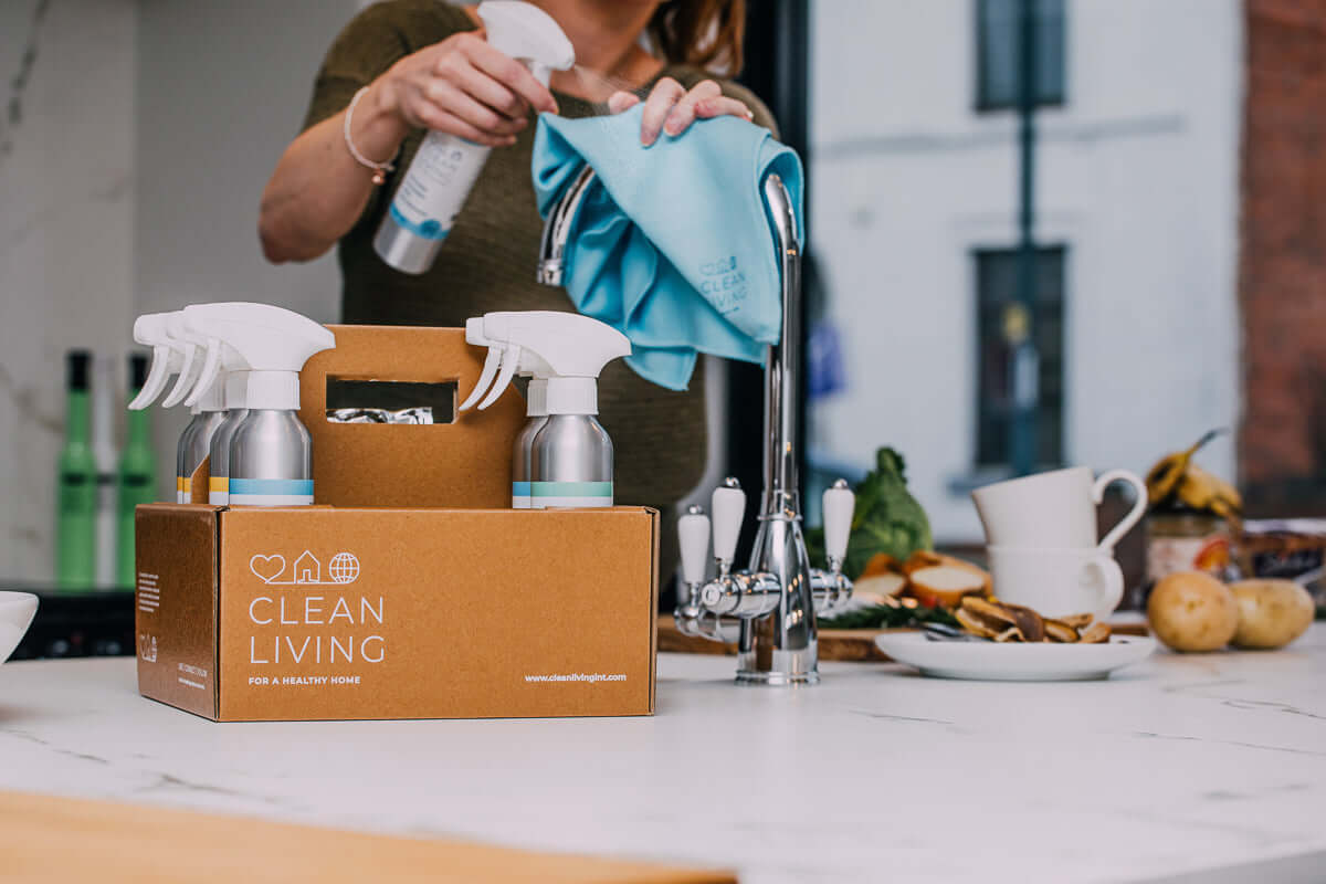 Eco Friendly, Probiotic, Complete Cleaning Kit displayed on a kitchen counter with cleaning supplies and a person using a cloth.