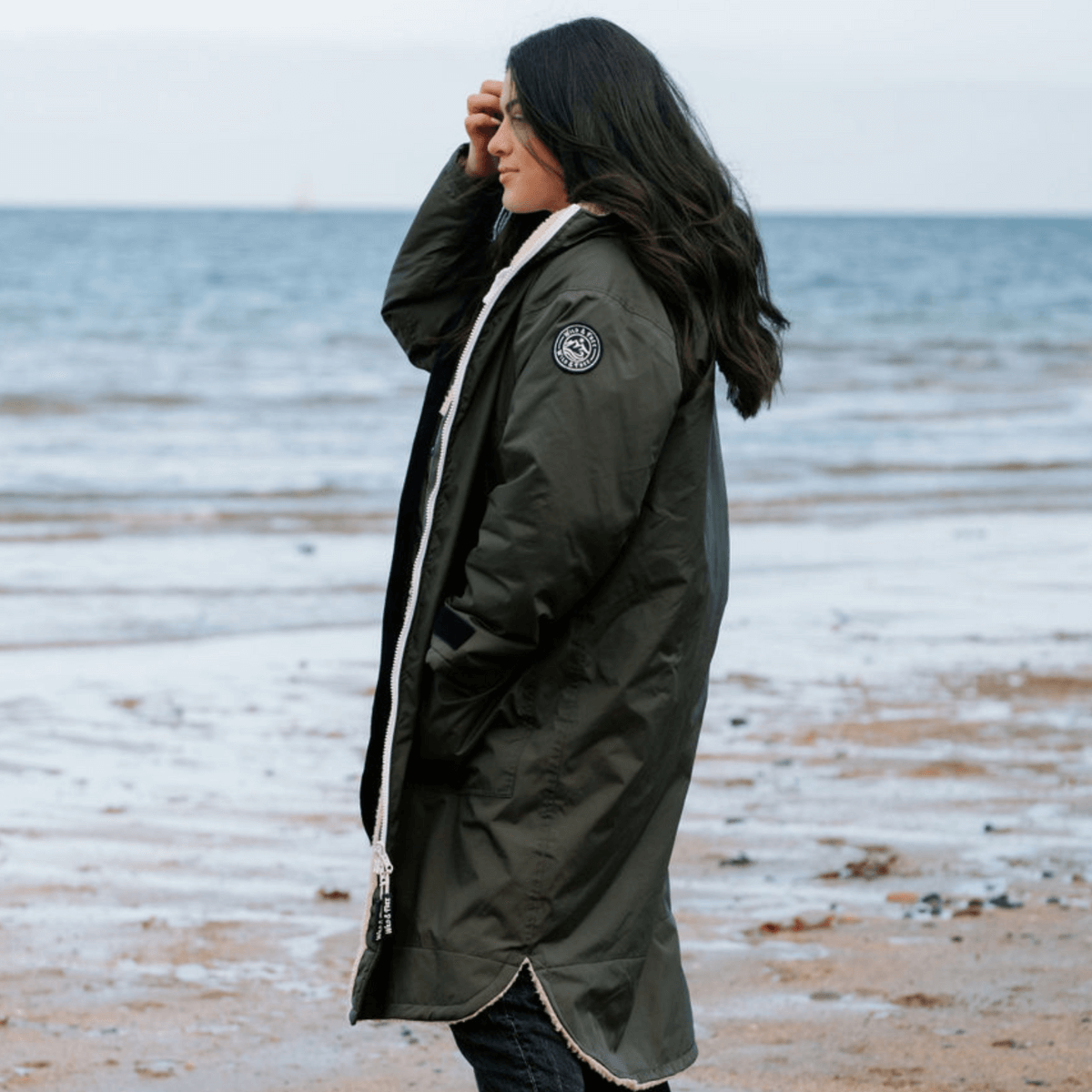 Raincoat & Changing Robe in One - The Classic Cobe Olive Green on a woman at the beach.